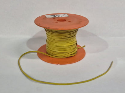 A spool of yellow leather lace wound around orange plastic spools, with a loose length of yellow cord extending to the left, set against a plain white background.